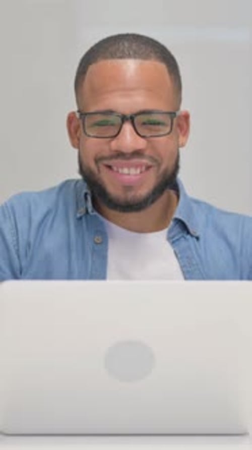 Smiling Man with Glasses Working on Laptop Indoors
