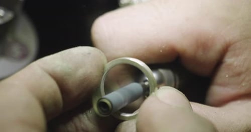 Close up of the hands of a goldsmith while he is working on a diamond ring. Concept: Style, fashio