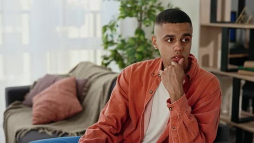 Thoughtful Young Man Sits Indoors During the Day