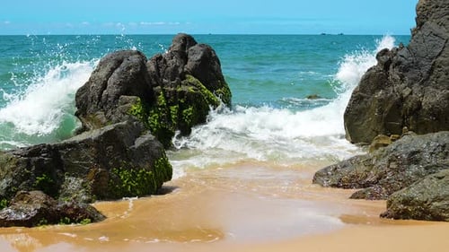 Olas del mar chocando contra la roca en medio de la playa