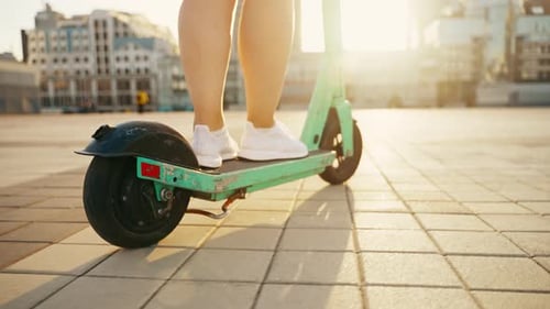 Vue des jambes d'une fille en scooter au coucher du soleil dans la ville