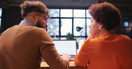 Professional Two Colleagues Analyzing Documents Using Laptop Working in Modern Office