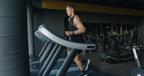 Young Man Running on a Treadmill in a Modern Gym Setting