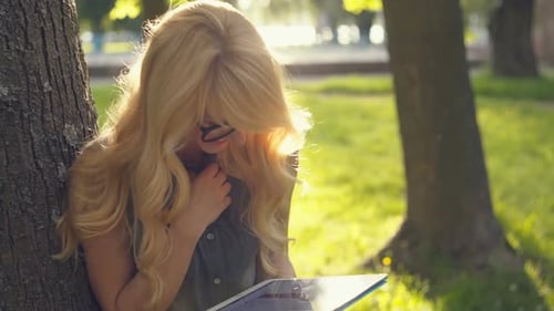 Happy Emotional Woman in Glasses Using Tablet Pc in the Summer Park