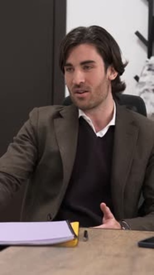 Man Talking and Gesturing at Desk in Office