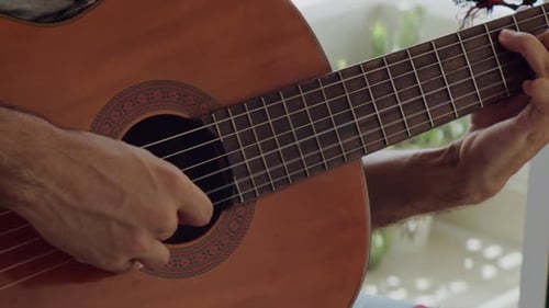 Close Up of Man Playing Acoustic Guitar at Home