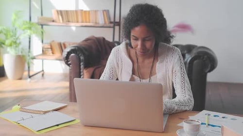 Young African American Woman Accountant Uses Laptop Sits at Office Table