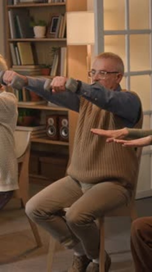 Senior Man Lifts Weights While Seated Indoors