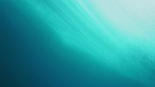 Underwater view of ocean surface as tendrils draw out across water from wave