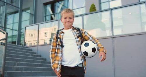 Portrait of middle school preteen student child boy with backpack and soocer ball looking at camera