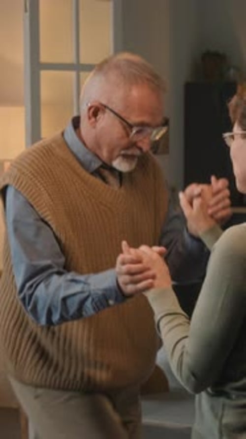 Affectionate Senior Couple Holding Hands and Dancing Indoors