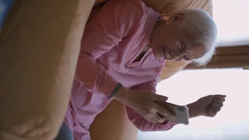 Senior Woman Using Smartphone While Sitting in Chair