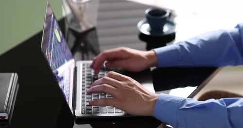Man working on laptop at desk in office, closeup