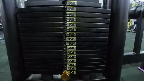 Ansicht des Cable Machine Weight Stack nach oben, wenn das maximale Gewicht angehoben wird. Der niedrige Winkel