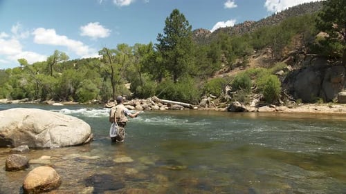 a man casting a fly fishing rod on a mountain stream while fly fishing.