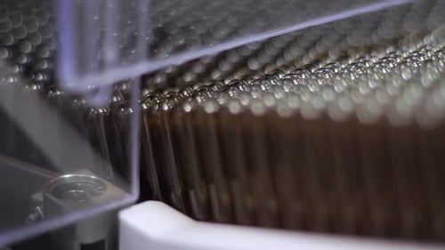 Glass medical ampoules travel along conveyor belt at pharmaceutical factory