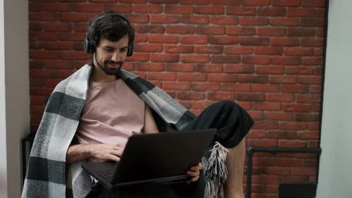 Man Working on Laptop at Home with Blanket