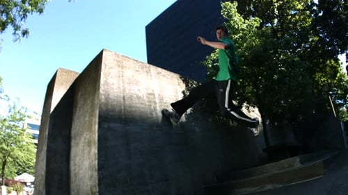 Athletic man doing parkour jumps off concrete structure