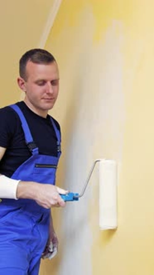 Renovierung des Zimmers. Porträt eines jungen Mannes, der die Wand bemalt.