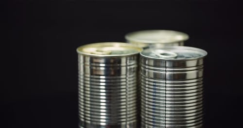 Three Shiny Metal Cans on a Dark Studio Background