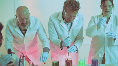 focused team conducts a chemical experiment - Researchers in safety gear work with vibrant beakers