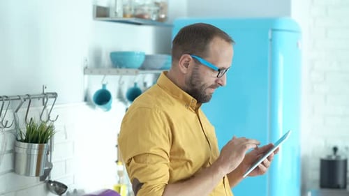 Man Uses Tablet Device in Colorful Home Kitchen