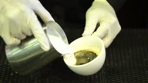 Pouring Milk into Espresso to Make Coffee Beverage