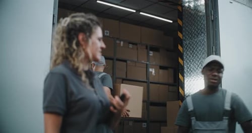 Multiethnic Workers Unloading Cardboard Boxes Female Manager Using Tablet Computer and Barcode
