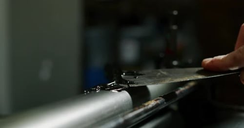 Slow motion close up of artisan papermaking master is working with antique ink printer to produce