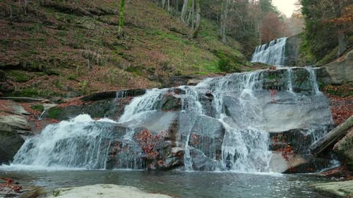 Beautiful cascading waterfall flowing in autumn forest. Water flowing over rocks in a beautiful