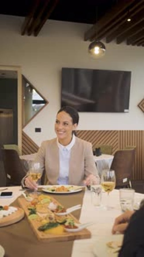 Portrait of businesswoman sitting with coworkers in restaurant during business lunch.