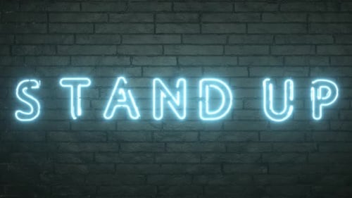 Stand Up neon sign on black brick wall background