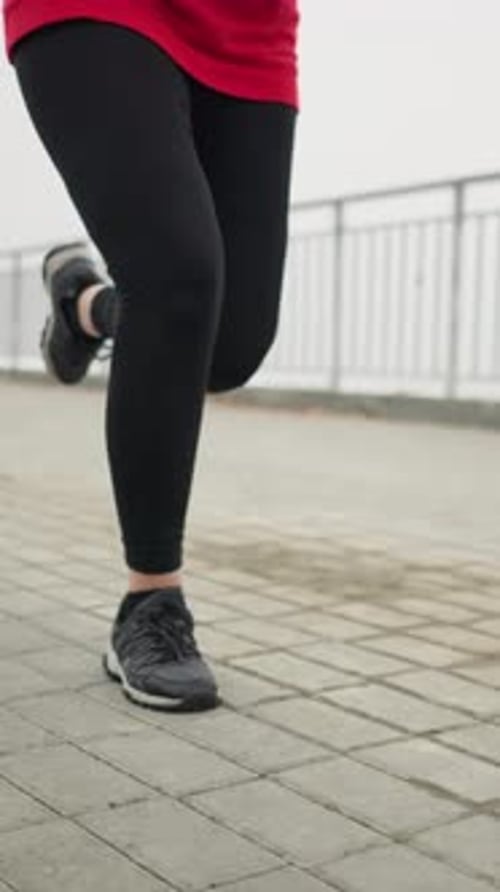 Leg View of Athlete Jogging in Black Sneakers and Leggings Near Railing