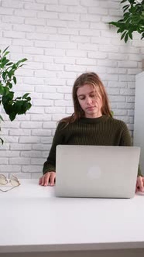 femme millénaire utilisant un ordinateur portable pour le travail assise à la table à la maison