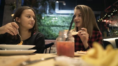 Teenage girlfriends enjoying food and drinks chatting in a cafe over tasty pizza