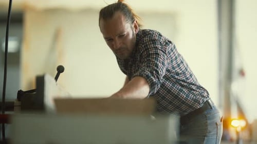 Concentrated Carpenter Cutting Wood in a Workshop