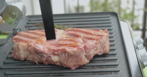 Juicy Beef Steak with Rosemary is Cooked on an Electric Grill