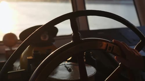 Captain Steering Ship Wheel on Bridge During Golden Hour Clip