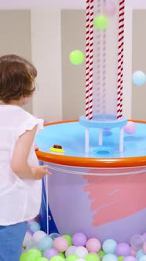 Child Playing with Ball Machine in Playroom
