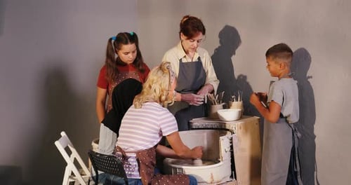 Woman at Pottery Wheel Teaches Art to Children