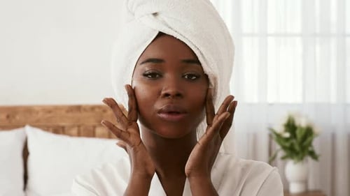 Woman Massaging her Face in Bedroom Close Up