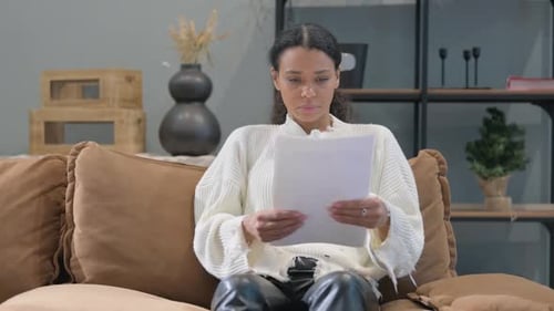 Woman Reading Document While Sitting on Sofa