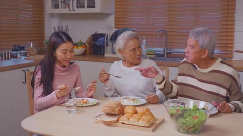 Three People Eating Meal at Kitchen Table
