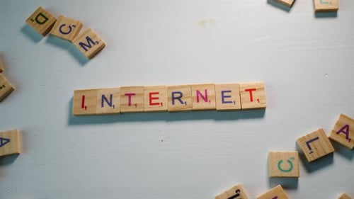 Someone spelling Internet with wooden letters on a white background with other scattered letters. Dr