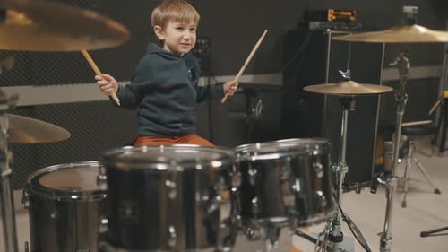 Young Boy Energetically Plays Drums in Music Studio