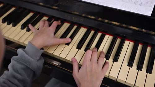 Child Plays Piano Keyboard with Sheet Music