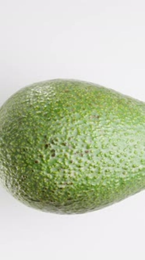 Vertical video. Green Ripe Avocado Rotates on a White Background, Looping. Top View, Isolated.