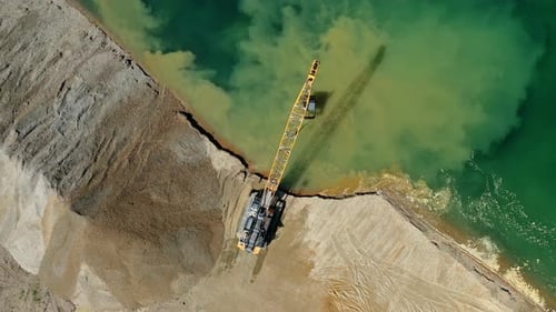 Axcavator moving sand and gravel pit on the lakeside, heavy industry and construction equipment.
