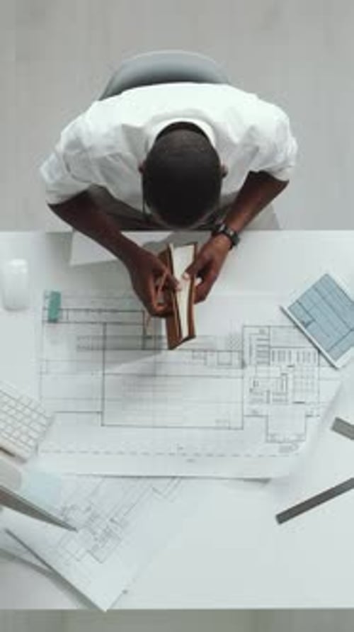 Architect Drawing Technical Blueprints in Office