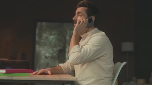 Man Talks on Phone at Desk in Office